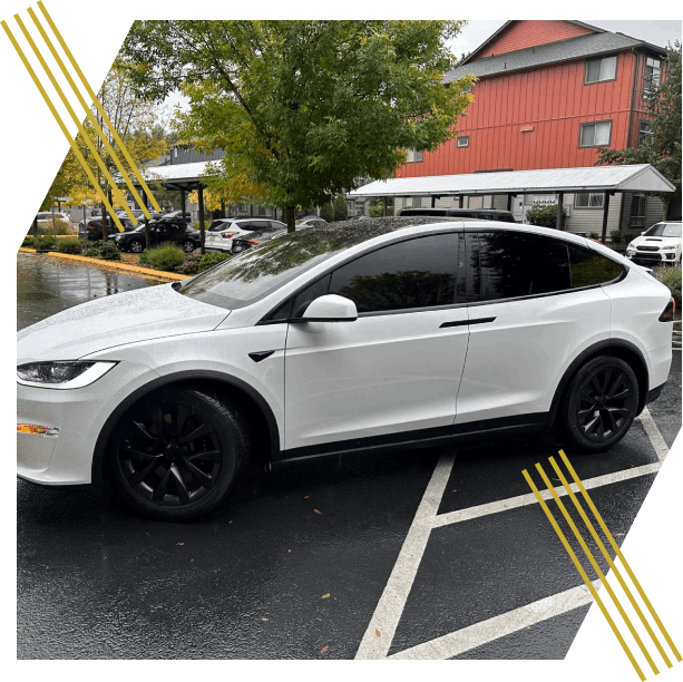 A sleek white electric SUV with tinted windows is parked in a Seattle neighborhood on a rainy fall day.